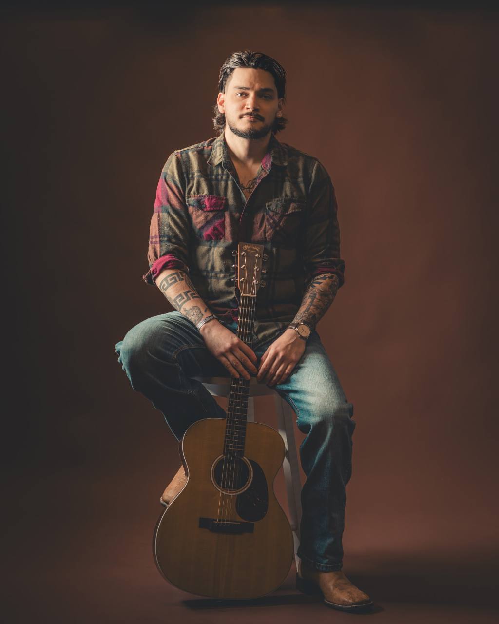 Anthony Segovia seated with an acoustic guitar