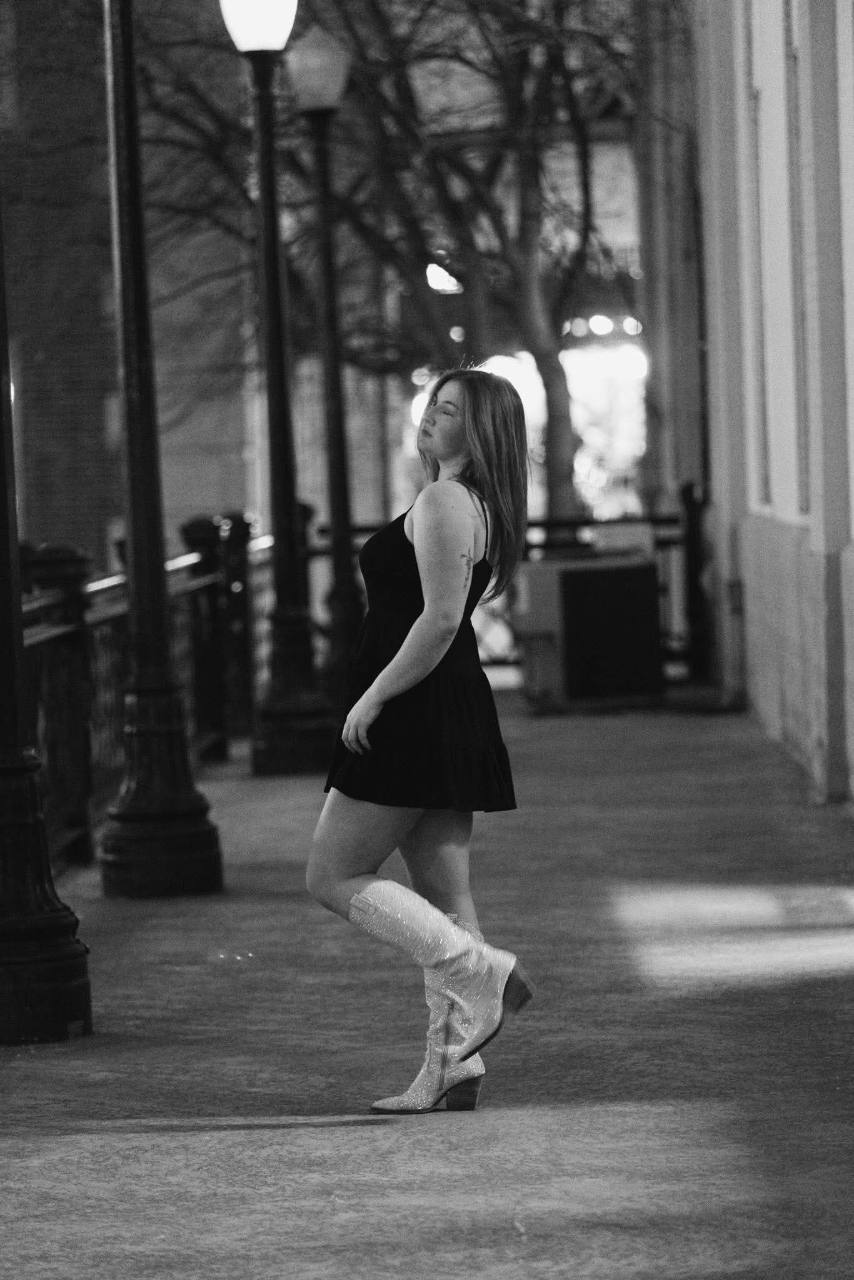 Briella Steiner wearing a black dress and white boots